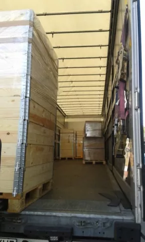 wooden crates stacked and secured inside a partially loaded truck trailer