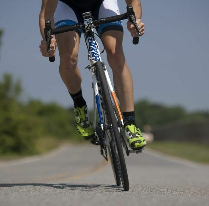 cyclist riding on open road wearing bright green cycling shoes