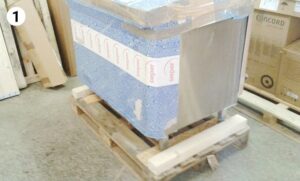 large metallic item wrapped in blue bubble wrap on wooden pallet